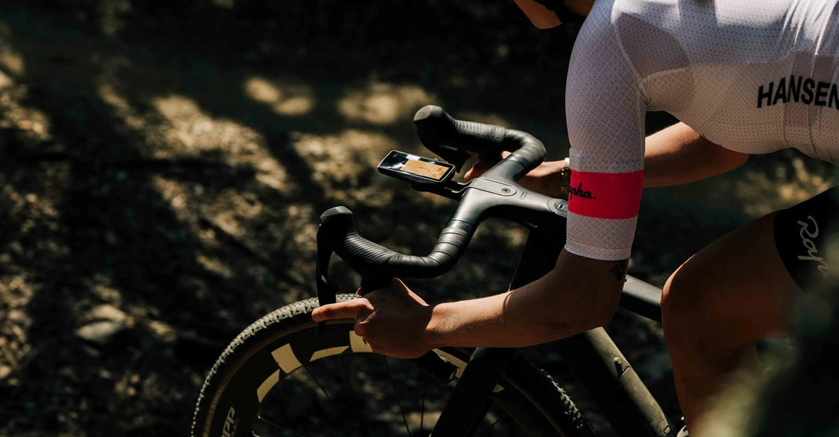 Person on a bicycle with a focus on the handlebar and gear shift, wearing a cycling outfit. Using Dura Bike Computer
